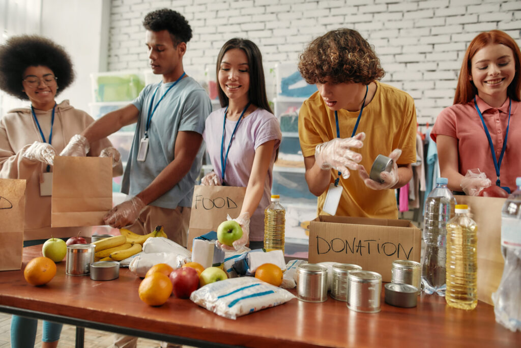 Volunteers preparing food and drink donations in paper bags.