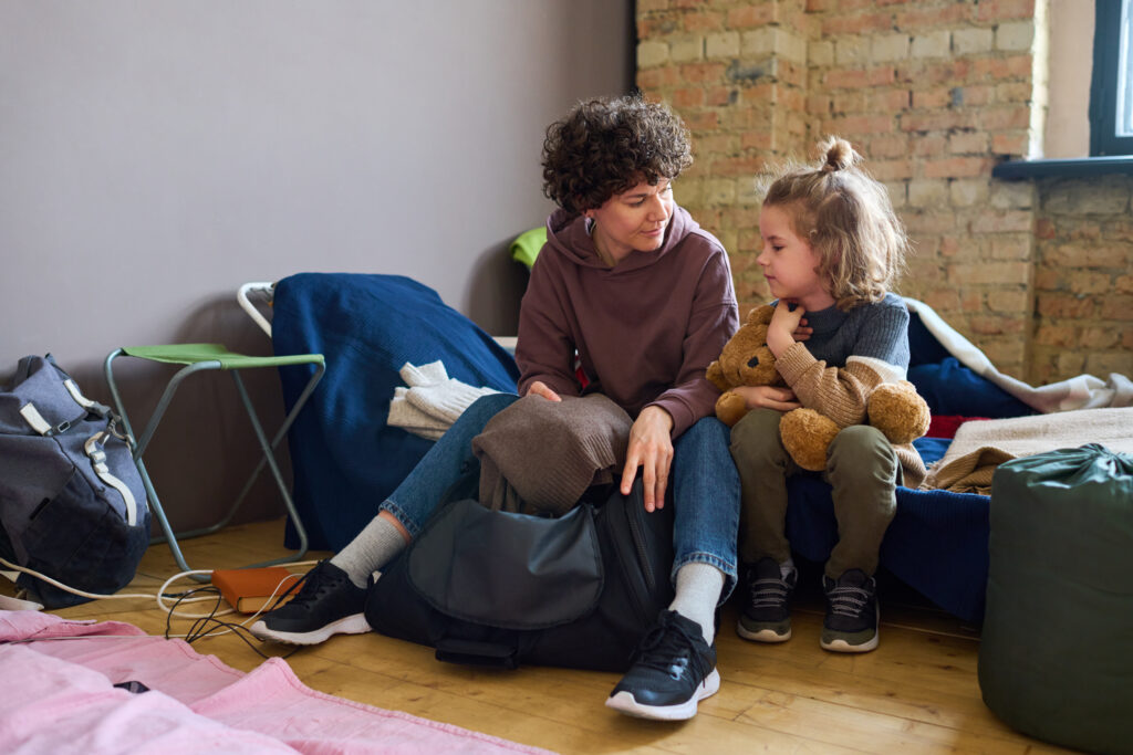 A mother and child receive warm clothing support in a shelter setting, representing rescue missions and homeless services.